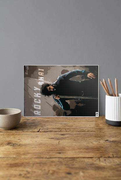 Kgf Rocky Bhai Sandalwood Movie Poster shown in A4 size on a wooden desk