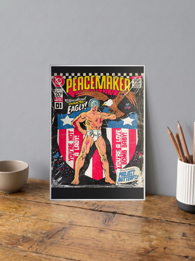 Peacemaker Eagly Cover DC Poster shown in A4 size on a wooden desk