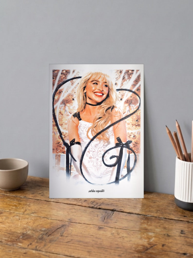 Sabrina Carpenter Glam Portrait Singers Poster shown in A4 size on a wooden desk